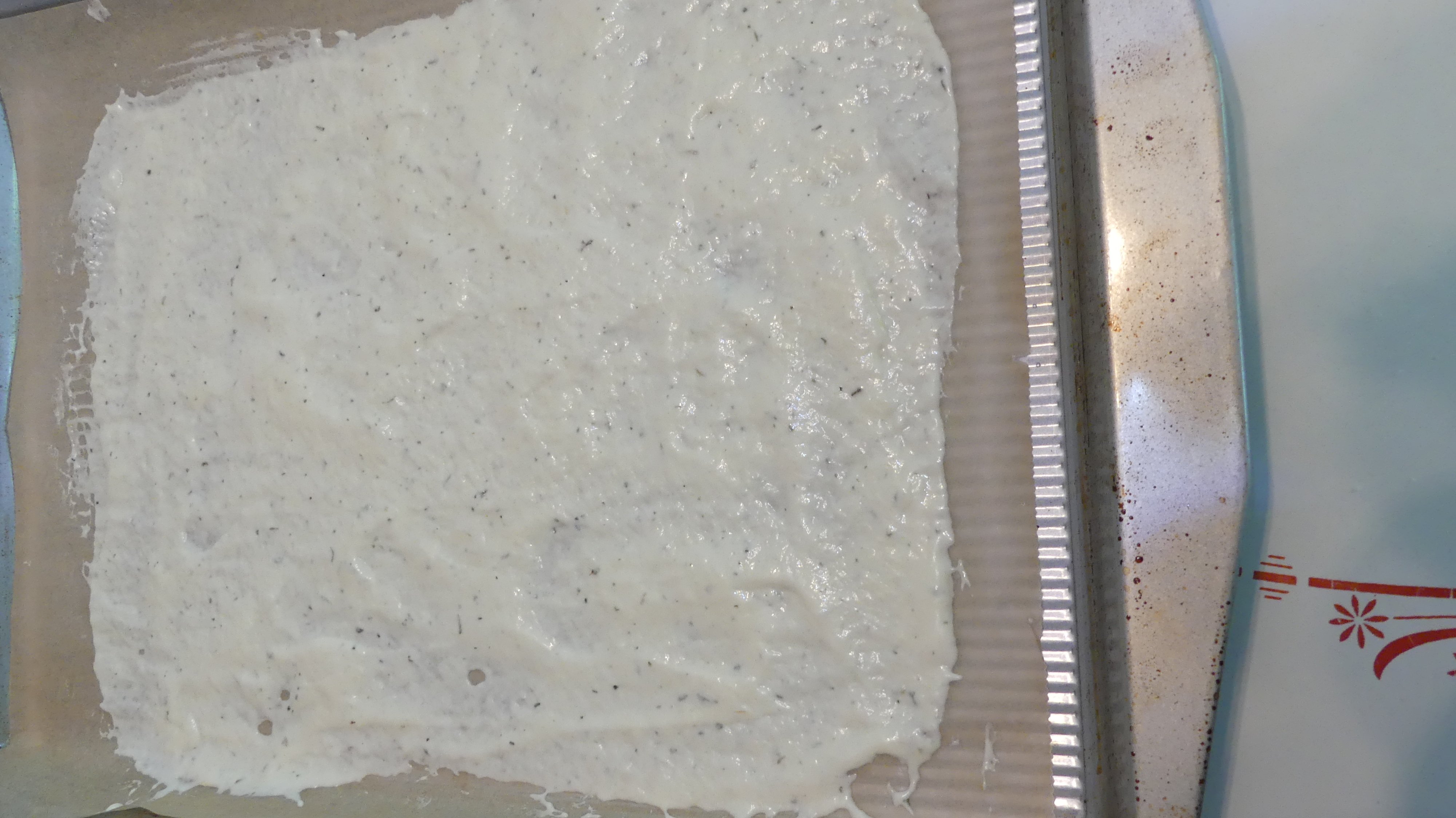 sourdough discard cracker mix spread thinly on a piece of parchment paper on a baking sheet