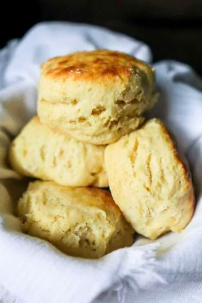 Biscuits are stacked on one another in a tea towel lined basket.