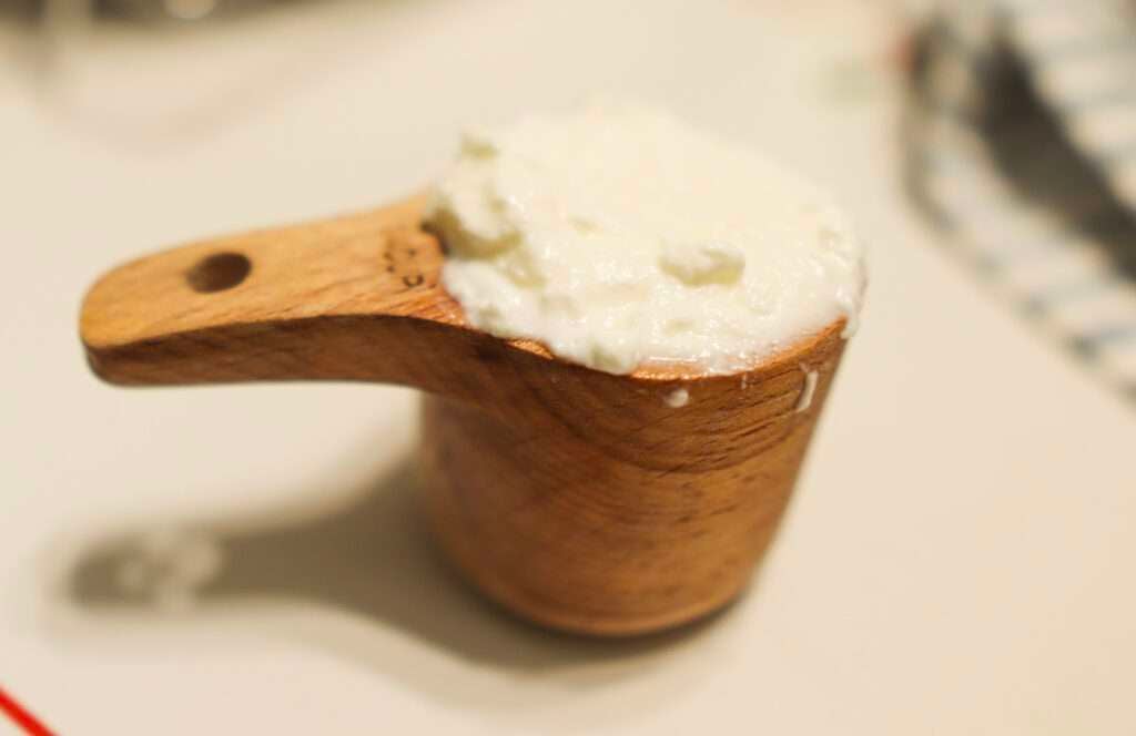 This is a wooden measuring cup full of homemade yogurt.