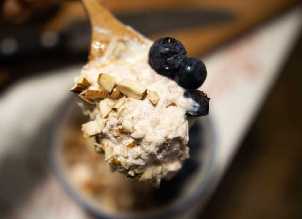 Homemade yogurt on a spoon with blueberries and almonds.