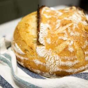 loaf of artisan bread on a striped blue kitchen towel