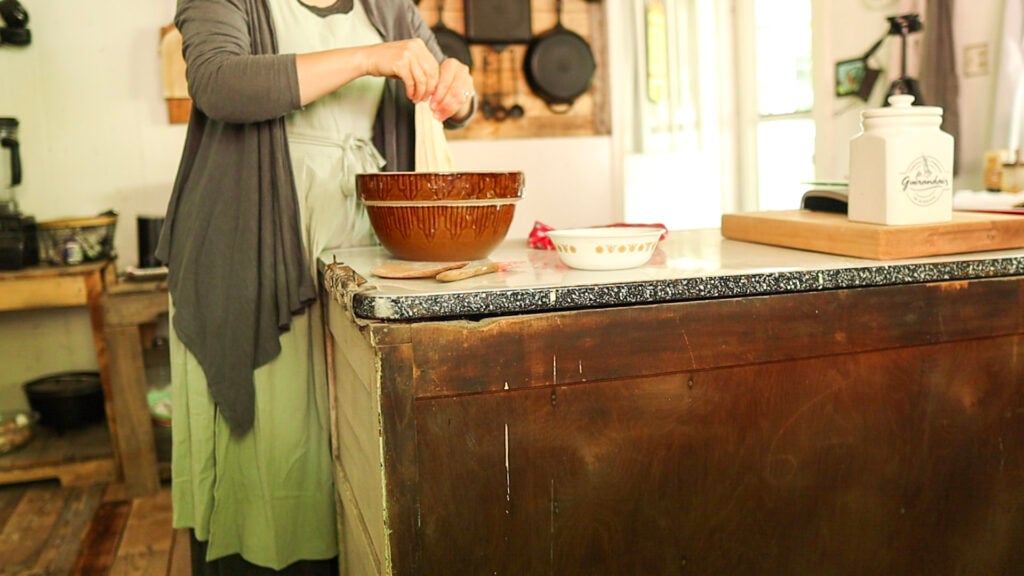 lady standing at counter stretching sourdough bread dough
