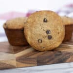 sourdough chocolate chip muffins on a cutting board with a red and white towel in the back ground.