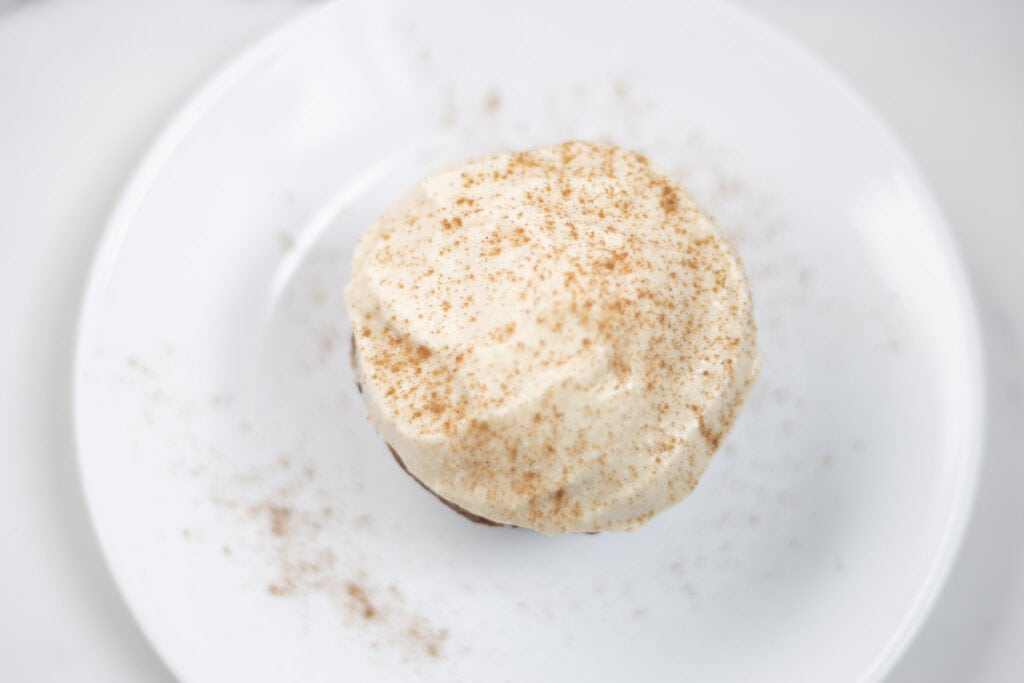 muffin with cream cheese frosting on top sprinkled with cinnamon