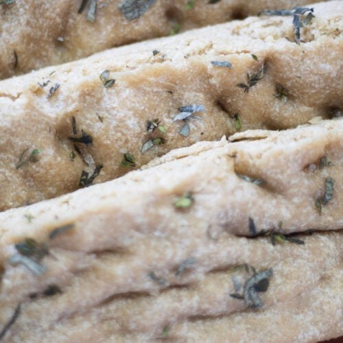 focaccia in slices with fresh herbs on top