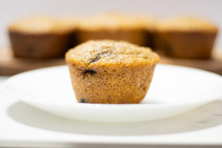 Berry muffin on plate in front of muffins on a cutting board