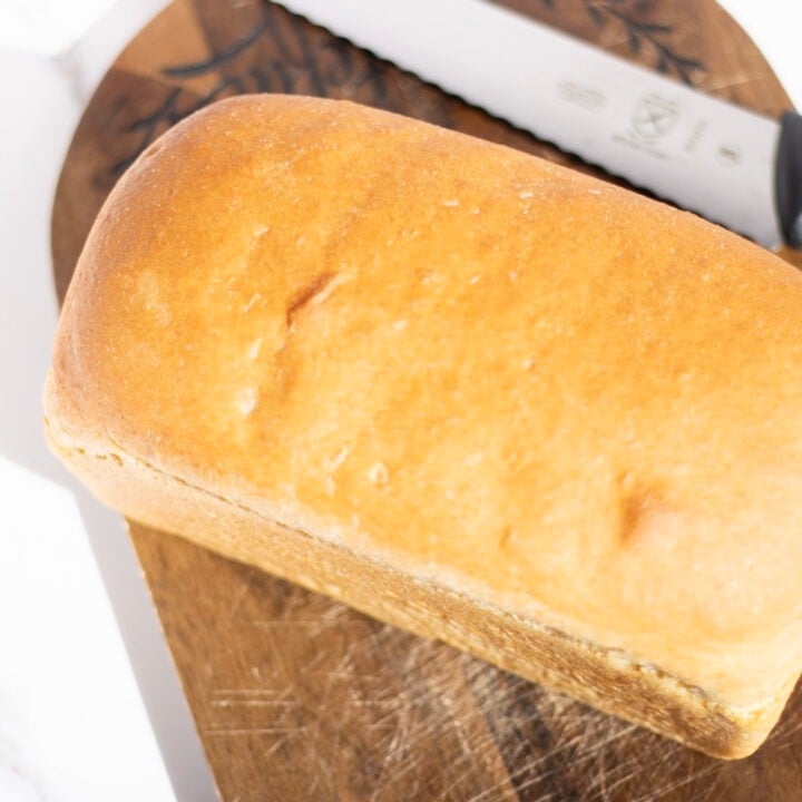loaf of bread on cutting board with bread knife beside it