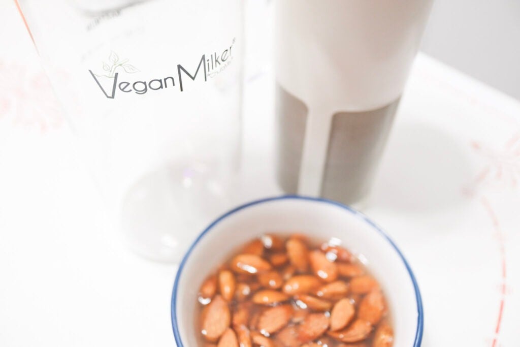 almonds soaking in water in front of a milk maker