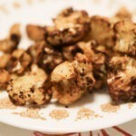 air fried cauliflower is laying on a white and gold dinner plate.