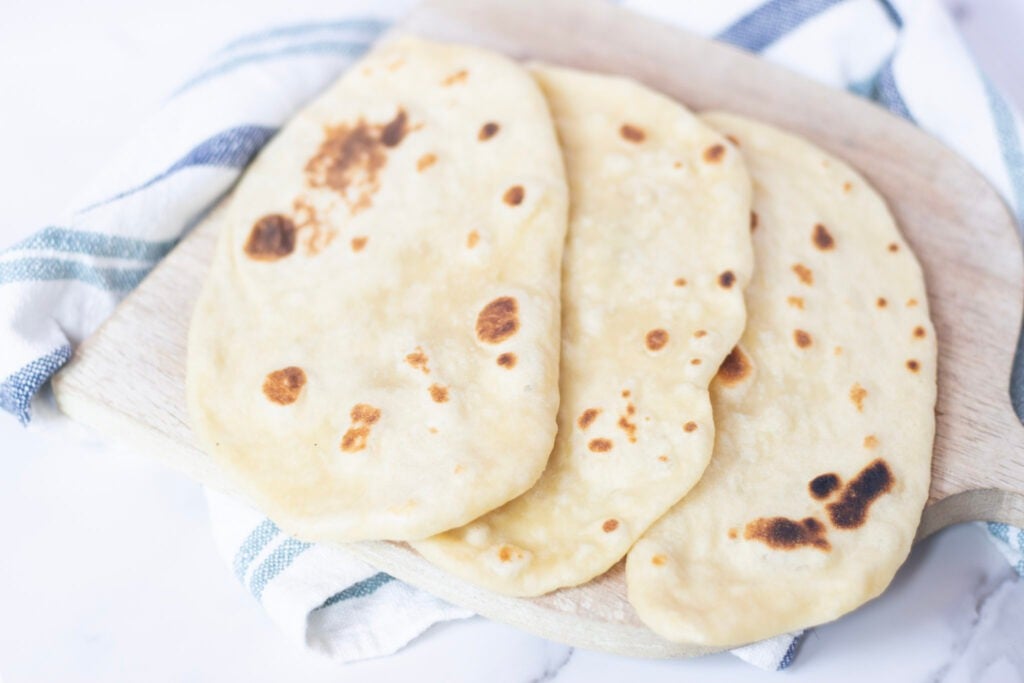 naan on cutting board with blue and white towel underneath