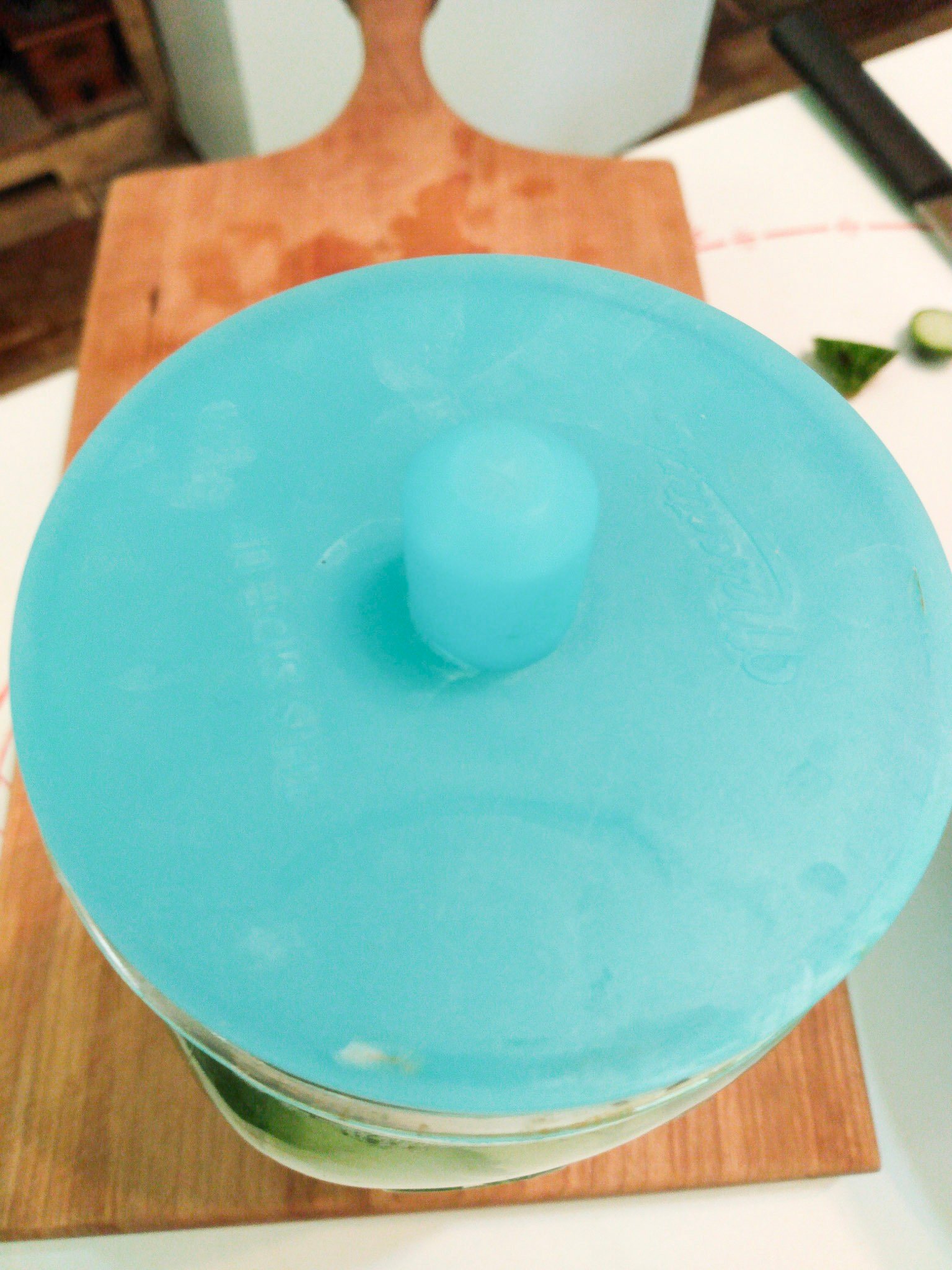 An airlock lid on top of a jar sitting on a cutting board.