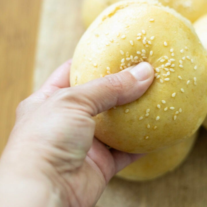 hand holding hamburger bun pressing in to show softness