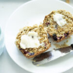 blueberry muffin cut in half with butter on top