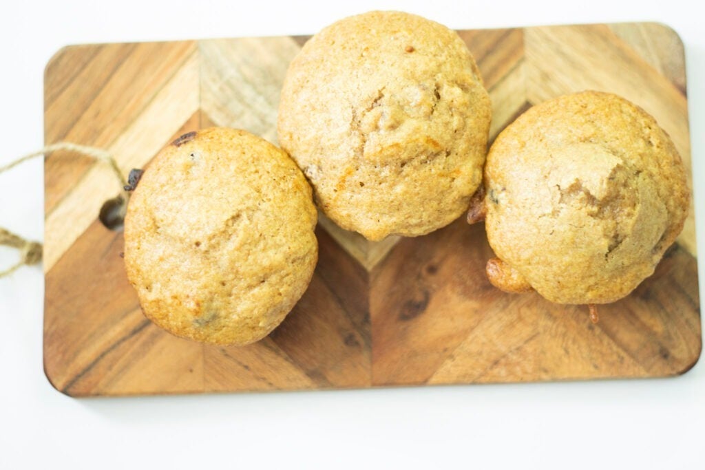 3 sourdough raspberry muffins on a cutting board over head shot