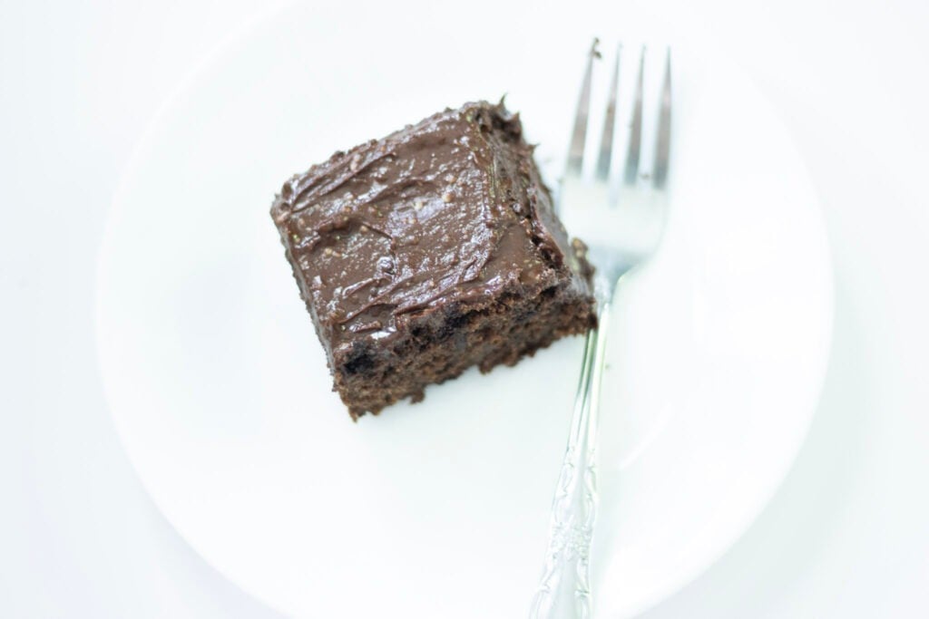 slice of sourdough chocolate cake on a white plate with a fork beside the cake