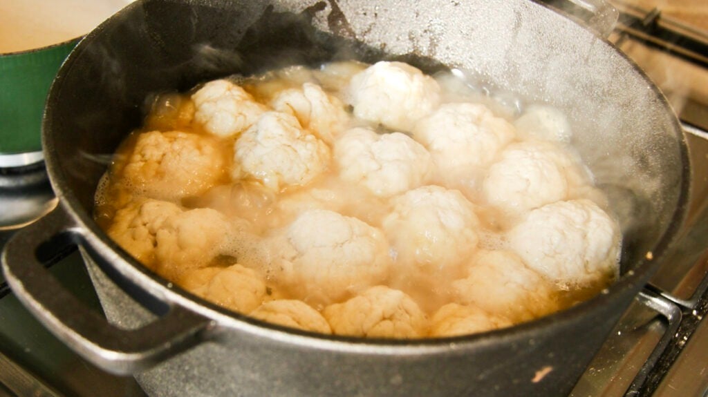 A metal pot with chicken and dumplings simmering