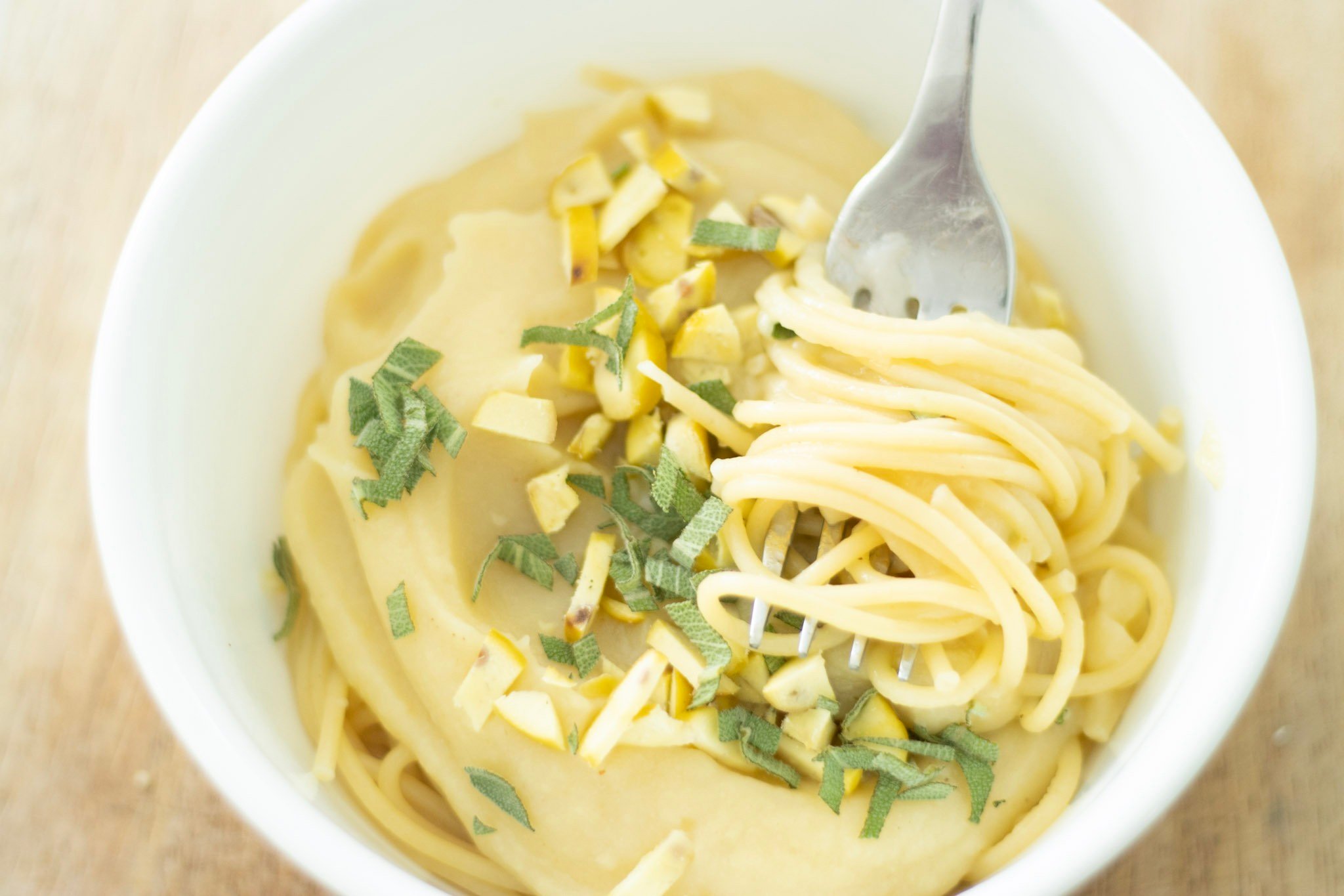 bowl of pasta with pumpkin pasta sauce, sage, and chestnuts