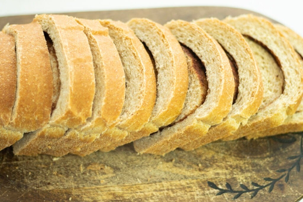loaf of sourdough cinnamon swirl bread sliced on cutting board