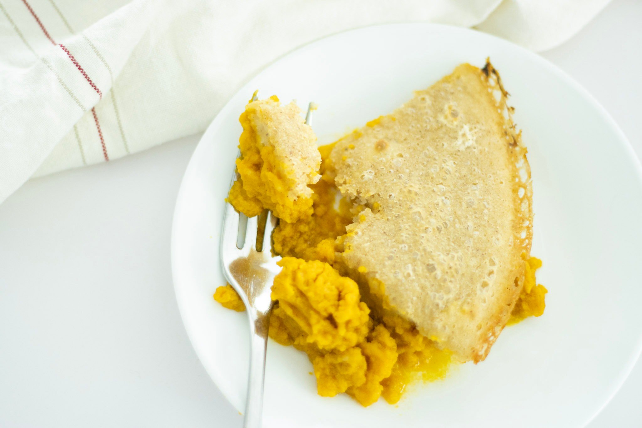 shot of sourdough pumpkin cobbler on a white plate with a fork