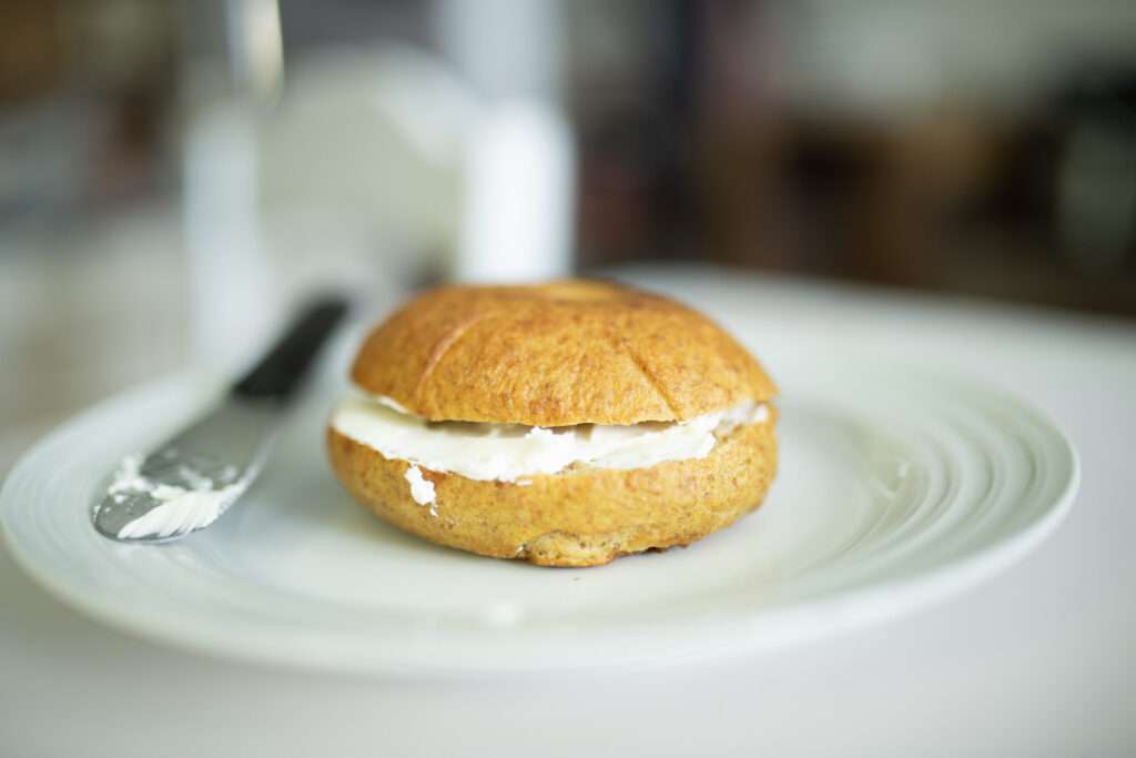 sourdough pumpkin bagel with cream cheese on a white plate