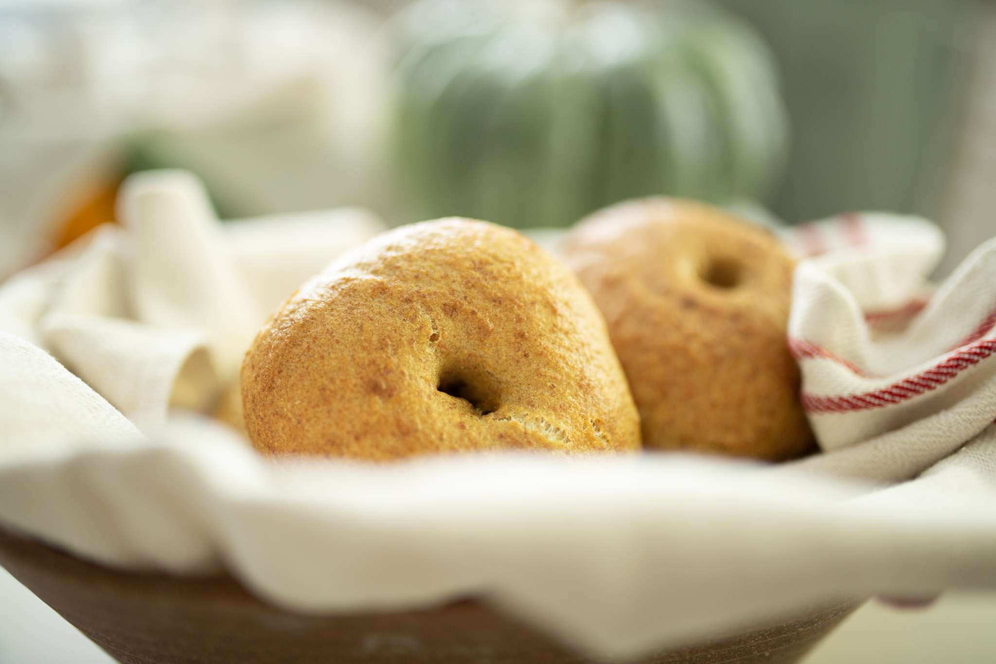 sourdough pumpkin bagels in a basket with a pumpkin in the background