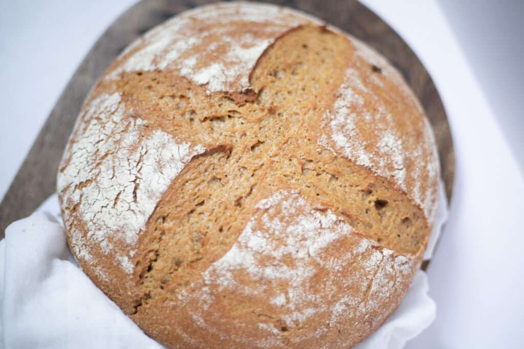 overhead shot of sourdough einkorn bread. It is golden brown with a lovely scoring pattern on top.