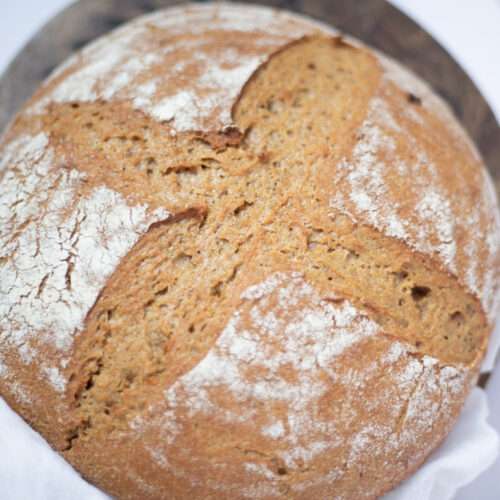 overhead shot of sourdough einkorn bread. It is golden brown with a lovely scoring pattern on top.