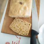 overhead shot of sourdough cinnamon raisin bread with one slice on a cutting board