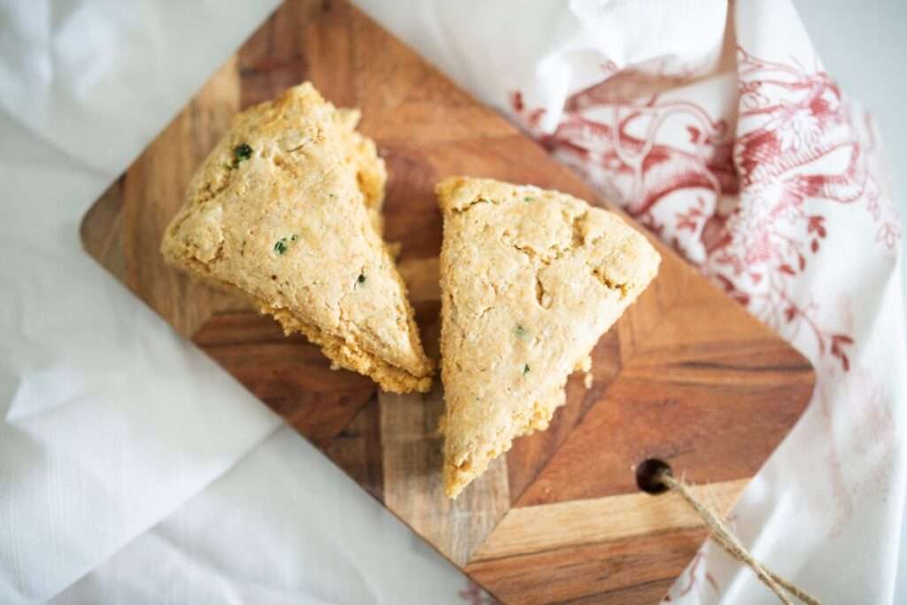 overhead shot of 2 sourdough jalapeno garlic scones on a board over a red and white towel