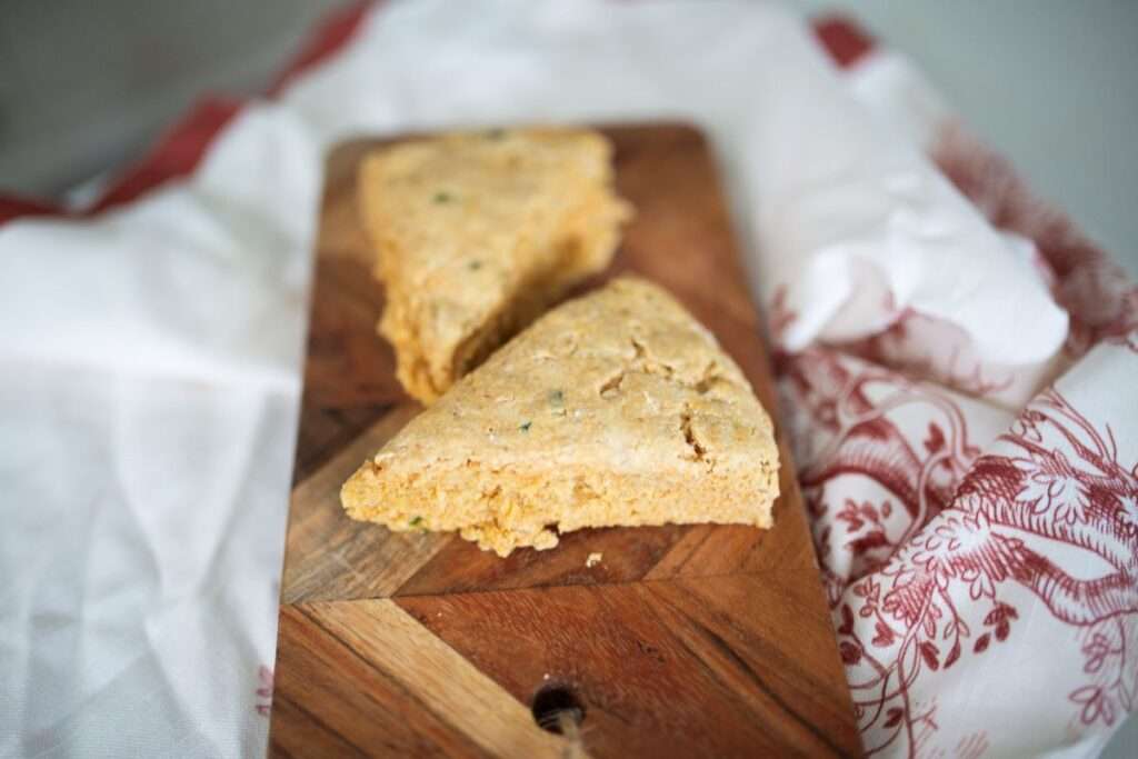 2 sourdough jalapeno garlic scones on a cutting board on a red and white towel