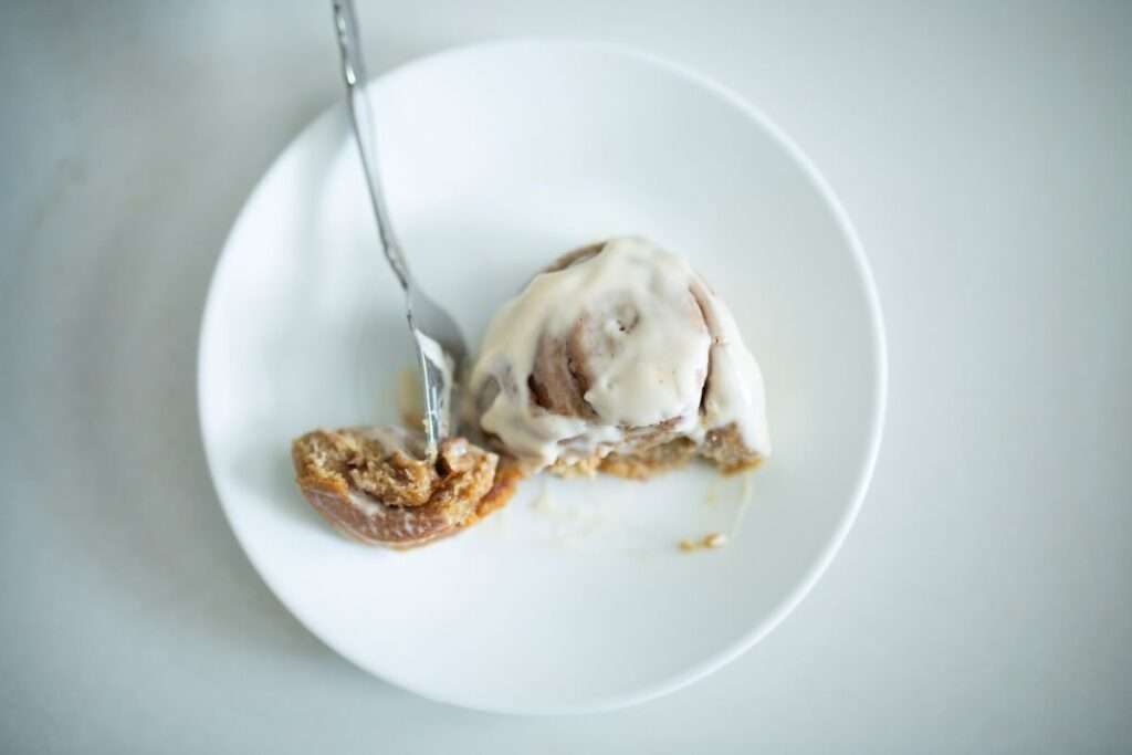 close over head shot of a sourdough pumpkin cinnamon roll on a white plate