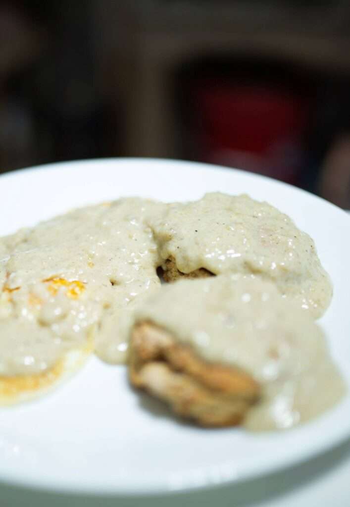 side view of sourdough breakfast gravy over biscuits and eggs
