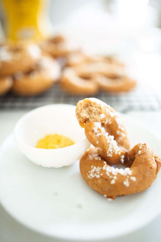 fresh milled sourdough pretzel cut in half on a plate with a small bowl of mustard