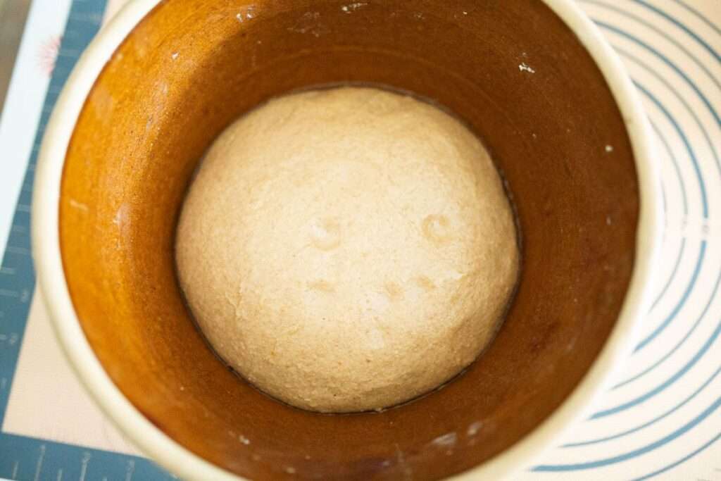 sourdough pumpkin cinnamon roll dough that has risen in a brown bowl