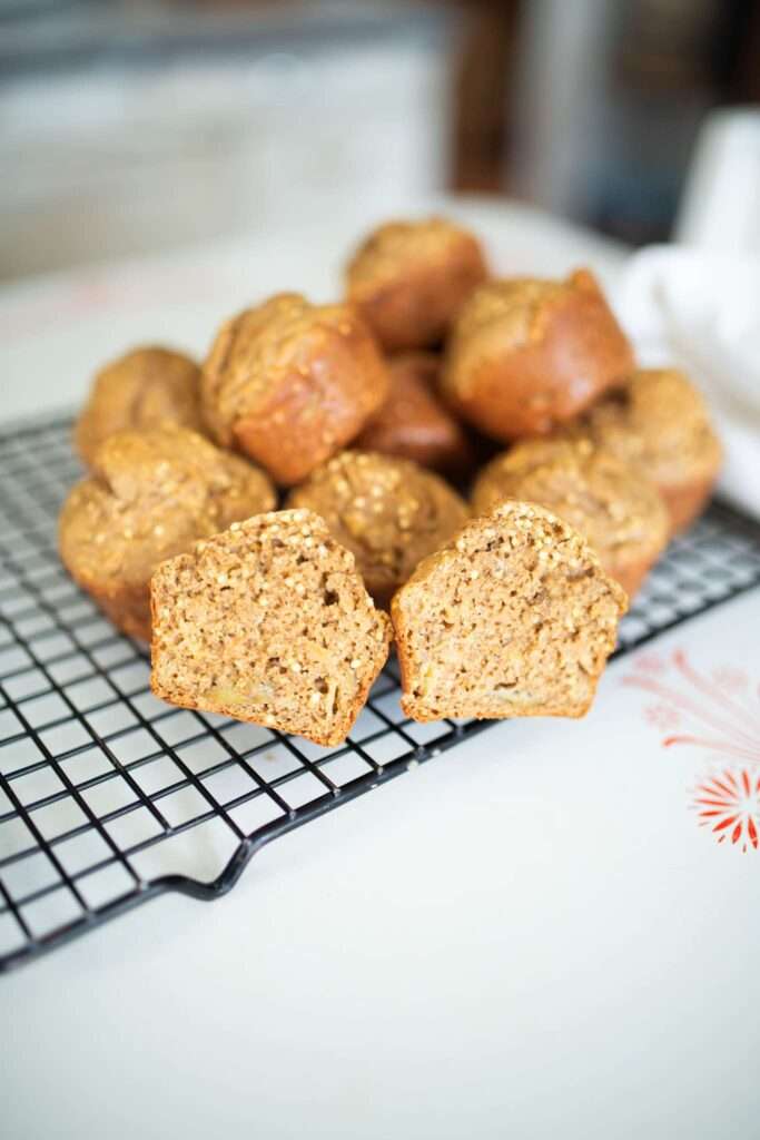 stack of fresh milled sourdough apple muffins with one cut in half to show the crumb