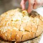 Man's hand pulling up a piece of sourdough pull apart bread