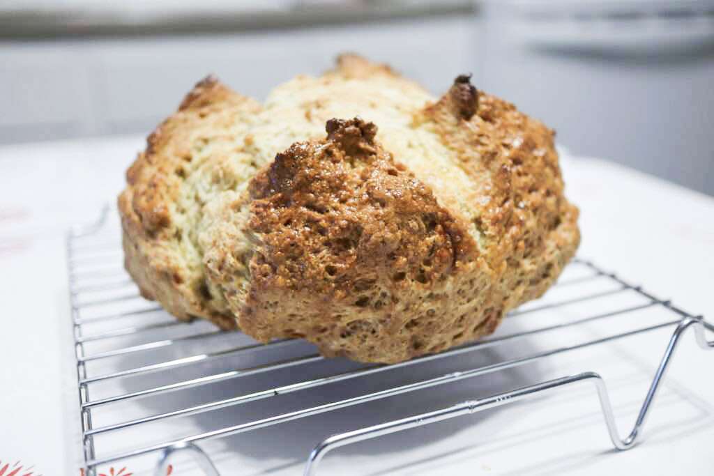 This is a loaf of irish soda bread on a wire rack.