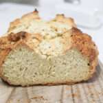 A loaf of irish soda bread on a wooden board sliced to show the crumb.