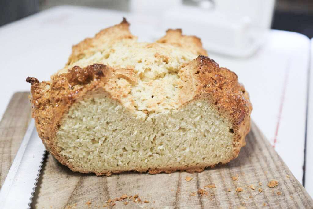 A loaf of irish soda bread on a wooden board sliced to show the crumb.
