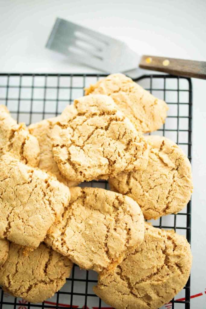 Stack of einkorn peanut butter cookies on a cooking rack with a spatula beside the rack