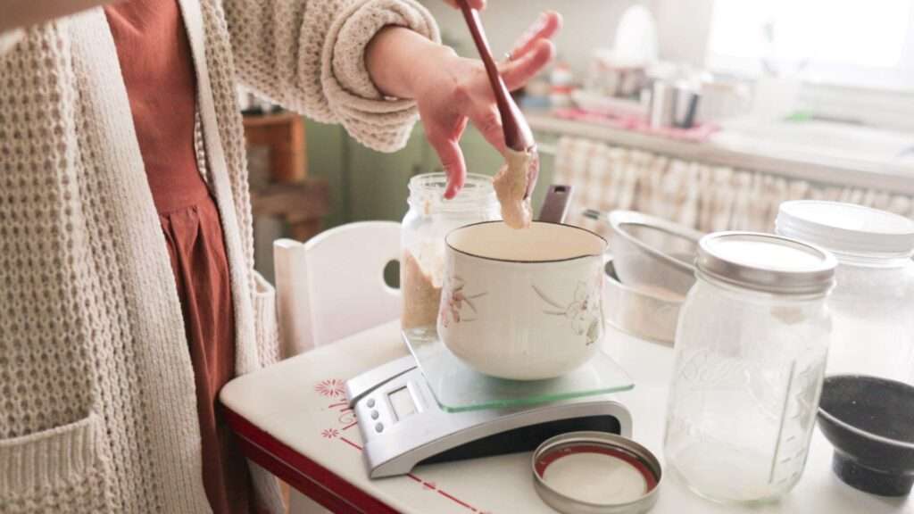 Putting a spoonful of stiff sourdough starter into water for a recipe