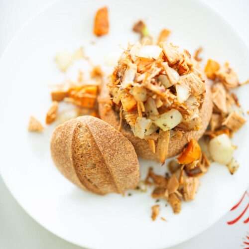 Overhead shot of a filled sourdough bread bowl on a white plate.
