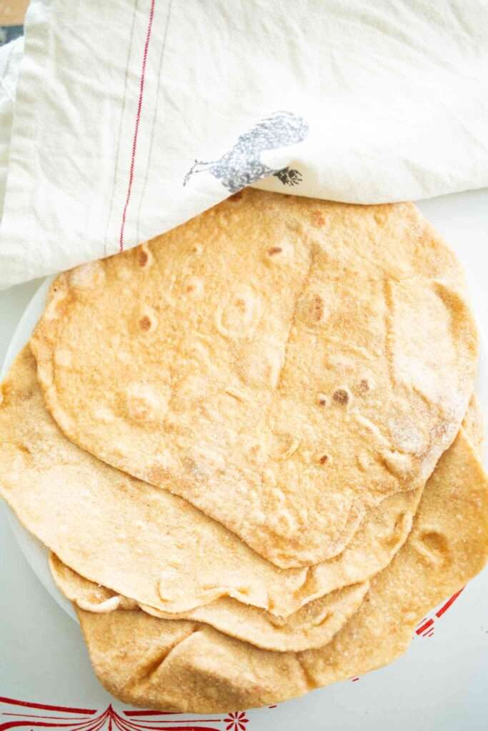 Sourdough einkorn tortillas on a plate with a white towel.