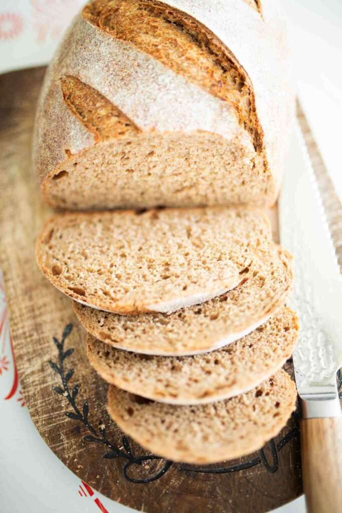 an overhead shot of a loaf of spelt sourdough artisan bread with half of it sliced to show crumb.