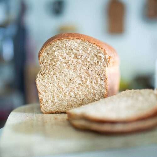 A sliced loaf of spelt sandwich bread on a cutting board.