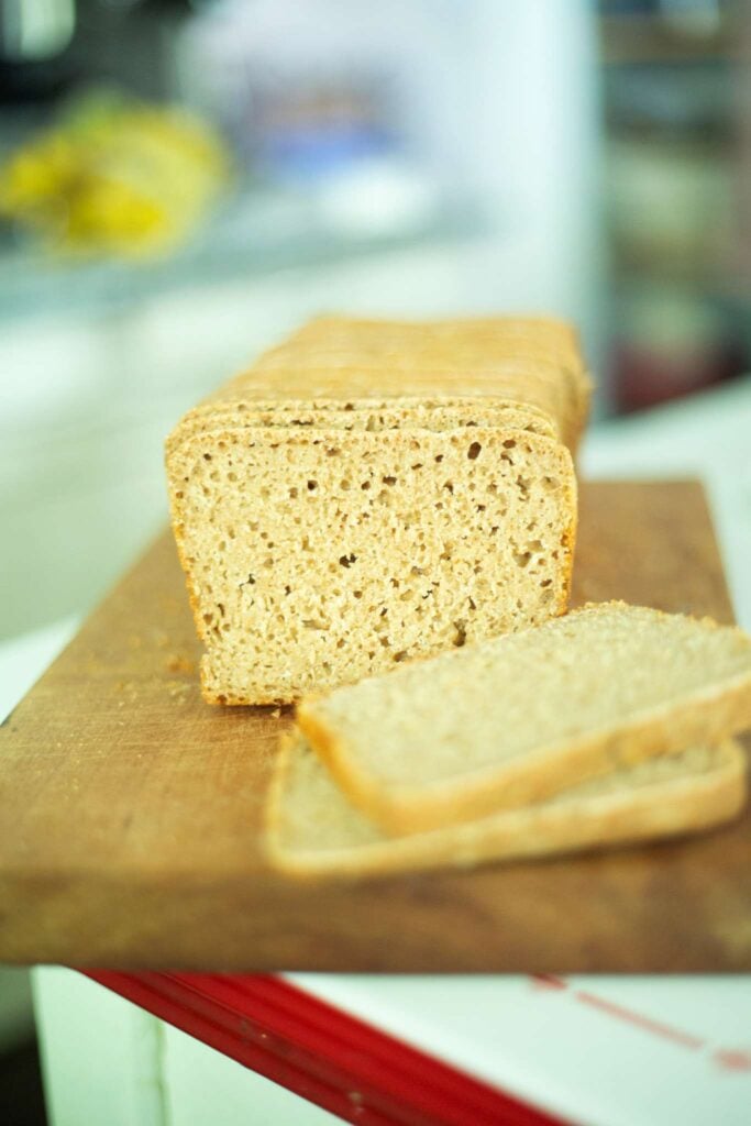 This a loaf of sourdough emmer bread that has 2 slices cut to show the crumb on a wooden board.