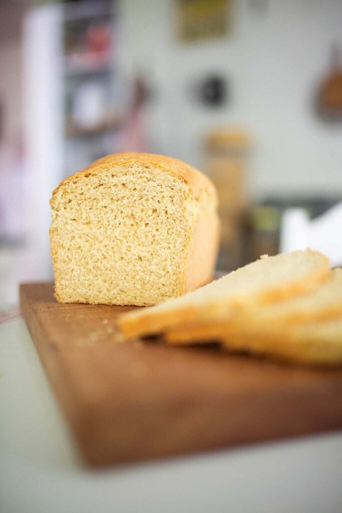 A loaf of Khorasan sandwich bread on a cutting board with a few slices blurred out in front of the rest of the loaf.