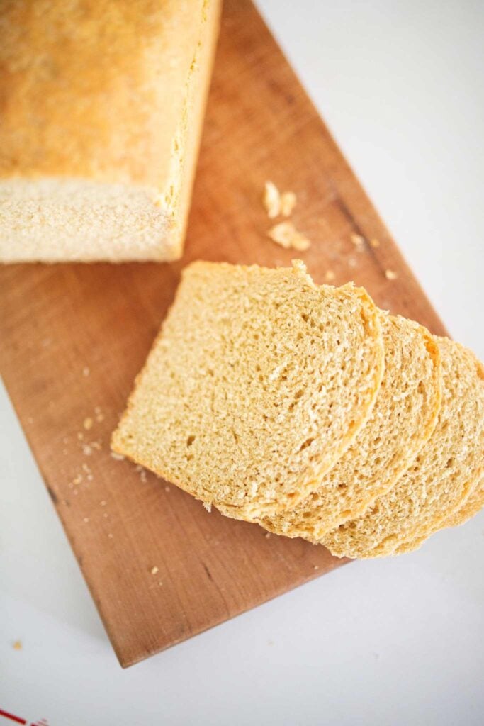 An overhead shot of a loaf of khorasan sandwich bread on a cutting board with a few slices.