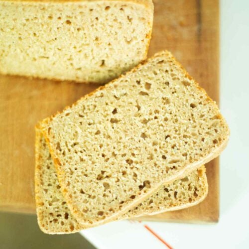 2 sliced of sourdough emmer bread with rest of loaf in the background on a cutting board.