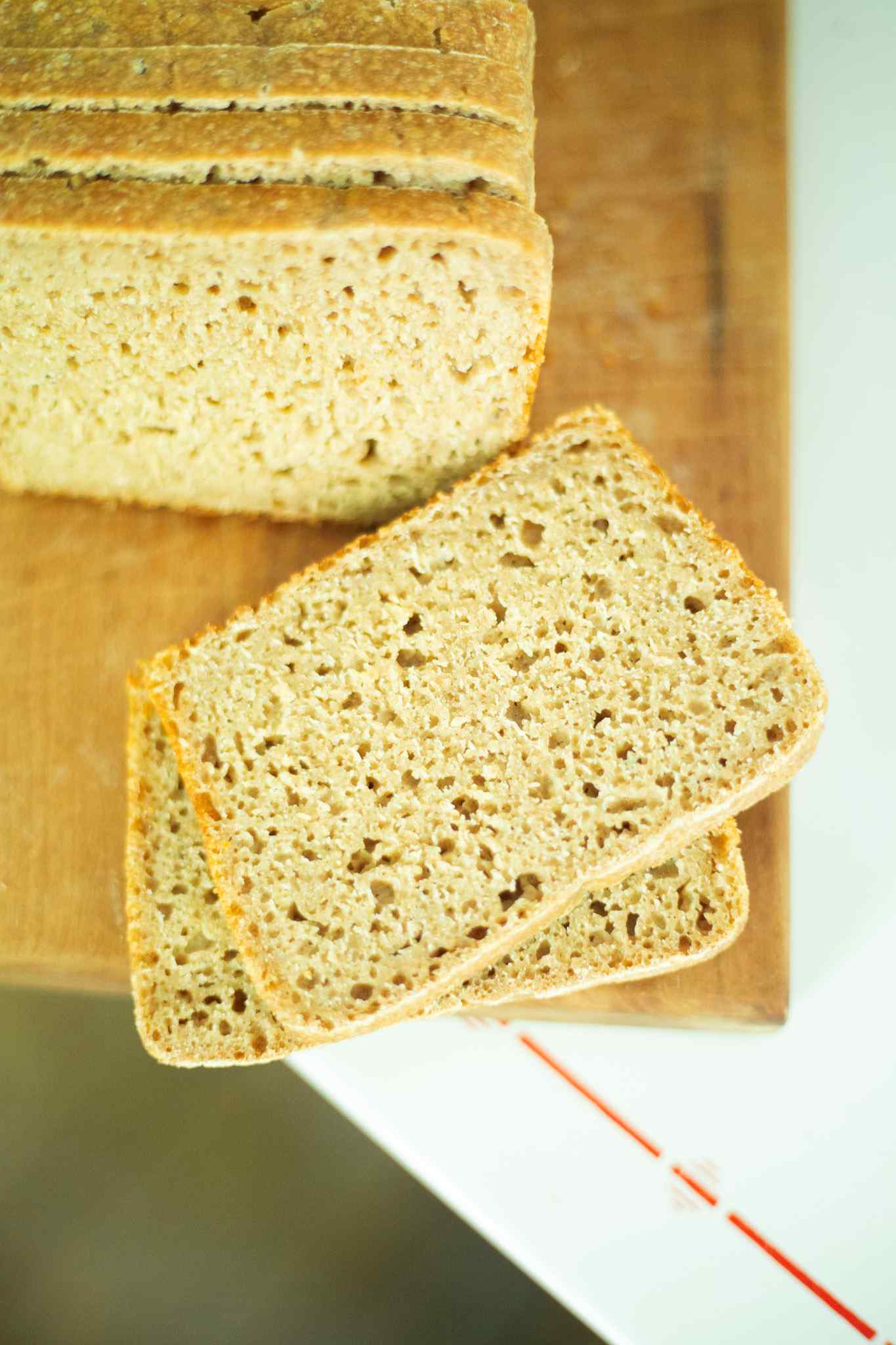 2 sliced of sourdough emmer bread with rest of loaf in the background on a cutting board.